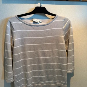 Grå och vit randig tröja från Massimo Dutti - Säljer en stilren grå och vit randig tröja från Massimo Dutti. Tröjan har trekvartsärmar och en rund halsringning, perfekt för en avslappnad look. Passar bra till både jeans och kjol.