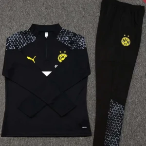 Dortmund tracksuit - Snyggt svart träningsset från Puma med Borussia Dortmunds logga. Tröjan har en halv dragkedja och mönstrade axlar. Byxorna har matchande mönsterdetaljer. Perfekt för fotbollsträning eller avslappnad stil.