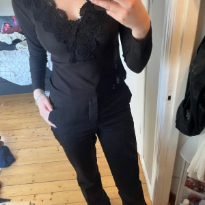 Svart festtopp med spetsdetaljer - Säljer den här svarta festtoppen med spetsdetaljer. Något nopprig längst ner som visas på sista bilden, i övrigt i fint skick! Säljer då den är för lite för mig.