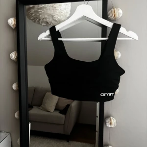Svart träningstopp/bh från Aim'n - Snygg svart träningstopp/bh från Aim'n med breda axelband och en stilren design. Perfekt för träning eller en avslappnad dag. Toppen har en liten logga på framsidan.