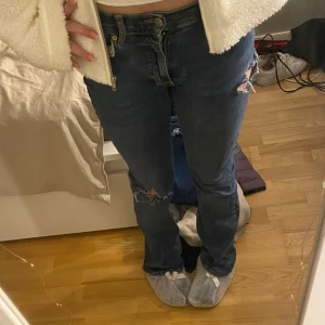 Blå jeans med slitningar - Säljer ett par blå jeans med coola slitningar på knäna. De är lågmidjade och bootcut. Jeansen är i en mörkare blå nyans. Pris kan diskuteras, kan lösa fler bilder om så önskas💗