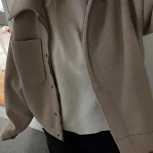 Beige jacka med knappar - Säljer en stilren beige jacka med knappar och stor ficka på framsidan. Jackan har en klassisk krage och är perfekt för en avslappnad look.