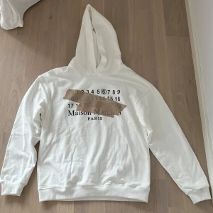 Maison Margiela hoodie  - Vit Maison Margiela hoodie i storleken 44/S, nästan oanvänd och i mycket bra skick. Passar lite större än S då den är baggy fit, pris kan diskuteras vid snabb affär!