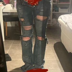  bootcut jeans med slitningar unisex  - Säljer ett par blå bootcut jeans med slitningar och hål över knäna och låren. Mått finns i bilderna (midja och innerben) skriv om ni har frågor!!❤️❤️