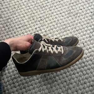 Maison Margiela Gats - Hej! Säljer dessa svart/bruna Margiela gatsen i strl 43. De är i använt skick men har mycket kvar att leverera, defekter finns som t.ex att sömmen där bak gått upp och lappen i är borttagen (finns kvar för den som vill legitchecka).                                Kom med bud eller byten!⭐️