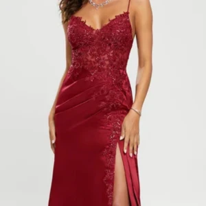 Vinröd långklänning med spets och slits - Säljer en elegant vinröd långklänning med smala axelband, spetsdetaljer upptill och hög slits på sidan. Klänningen har figurnära passform och v-ringad urringning, perfekt för fest eller bal. säljer eftersom den är för stor på mig🩷 pris kan diskuteras 