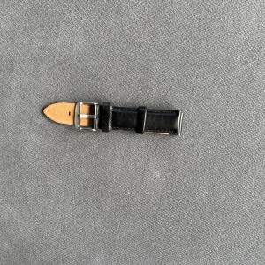 Svart läderarmband Daniel Wellington - Säljer ett svart klockarmband i äkta läder från Daniel Wellington. Armbandet har silverfärgat spänne och klassisk design med snygga sömmar. Passar perfekt till DW-klockor och ger en stilren look.