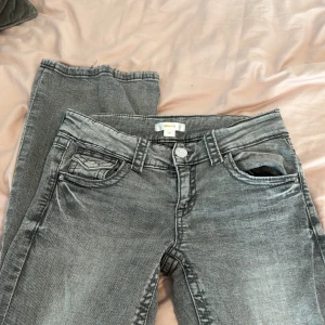 Grå jeansbyxor från Gina Tricot - Säljer ett par grå jeansbyxor från Gina Tricot i storlek 158. Byxorna har klassisk femficksdesign med lock på myntfickan och bakfickorna, samt knäppning fram. Snygg tvättad look och raka ben.