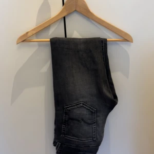 Jack and Jones jeans grå/svarta  - Säljer ett par svarta jeans från Jack and Jones. Byxorna är använda men fortfarande i utmärkt skick. Byxorna är i modellen slim Glenn. Hör av er vid minst fråga eller fundering. 