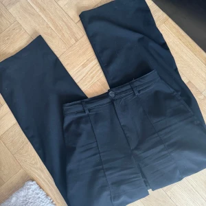 Svarta kostymbyxor från Pull&Bear - Snygga svarta kostymbyxor från Pull&Bear Black Label. Byxorna har raka ben, pressveck och klassisk midja med knapp.