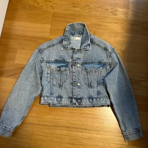 Jeansjacka - Säljer en blå jeansjacka från g perfect jeans i storlek S. Jackan har klassisk krage, två bröstfickor med knappar och silverfärgade detaljer. Perfekt att slänga över en hoodie eller t-shirt för en cool look.