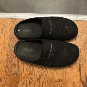 Grattis frakt - Svarta, enkla tofflor i syntetmaterial med platt sula och rund tå. Perfekta att glida i hemma för en chill vibe. Klassisk slip-in modell utan några extra detaljer