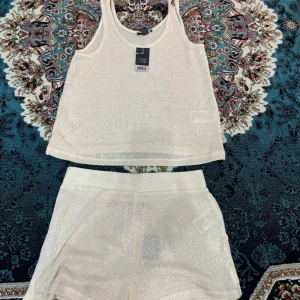 Beige stickad linnetopp med shorts - Säljer en beige stickad linnetopp med rund halsringning. Toppen är ärmlös och har en luftig, lätt transparent struktur som passar perfekt till varma dagar. Enkel och stilren design som är lätt att matcha. Inklusive matchande shorts. Ska användas som pyjamas.