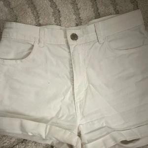 Vita jeansshorts - Snygga vita jeansshorts med klassisk femficksdesign och knappgylf. Shortsen har normal passform och är perfekta för varma dagar. Stilrena och enkla att matcha med olika toppar.
