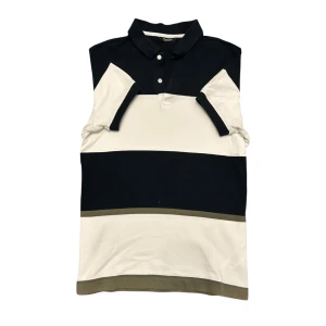 Randig pikétröja från Massimo Dutti - Snygg randig pikétröja från Massimo Dutti i svart, vit och beige. Tröjan har en klassisk krage med knappar och korta ärmar. Perfekt för en stilren look.