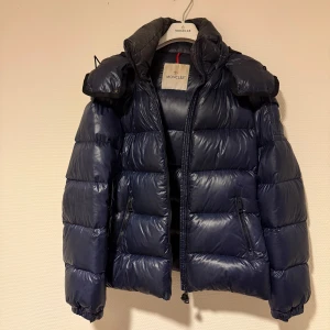 Moncler jacka - Säljer min moncler jacka i använt skick. Har ett hål i höger kant längst ner som försökts lagats(bild 2 och 3). ”Serien” har åkt av men finns kvar om man vill laga. Köpt på Vestiaire collective och även äktighetsverifierad av dem💕kan gå ner i pris vid snabb affär🫶🏼