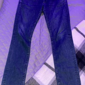 G-Star RAW Midge Skinny jeans - Säljer ett par klassiska blå skinny jeans från G-Star RAW, modell Midge Skinny WMN. Jeansen har normal midja, raka ben och snygga detaljer med G-Star-logga på fickan. Perfekta för dig som gillar en tidlös och stilren look.