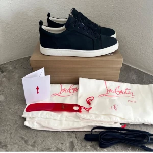 Svarta sneakers från Christian Louboutin - Säljer ett par mörkblåa fräscha skor från Christian Louboutin med klassiska röda sulan och den eftertraktade vita sulan .kommer med extra skosnören, dustbags och originalkartong. Perfekta för dig som gillar lyxiga och stilrena skor