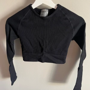 Svart ribbad topp från Aim'n - Säljer en svart croppad långärmad topp från Aim'n. Tröjan är ribbad och har en tight passform. Aldrig använd 
