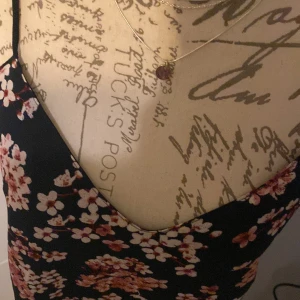 Blommig linnetopp från Paul Edition - Säljer en söt blommig linnetopp från Paul Edition i svart med rosa och vita blommor. Toppen har tunna axelband och v-ringning både fram och bak. Perfekt för varma dagar och enkel att matcha med jeans eller kjol.