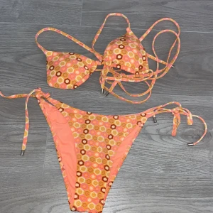 Mönstrad bikini från Censored - Säljer en färgglad bikini från Censored i storlek S. Bikinin har ett hexagonmönster i orange, rosa och bruna toner. Klassisk trekantsmodell med knyt både upptill och i sidorna på underdelen. Materialet är syntet och känns mjukt mot huden. HAR ALDRIG ANVÄNT!!