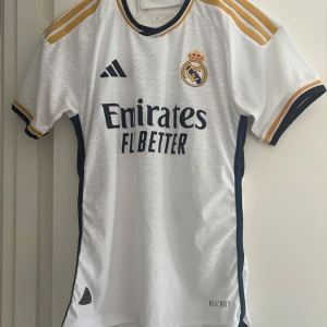 Real Madrid fotbollströja Vini Jr 7 - Säljer en vit spelarversion Real Madrid matchtröja med Vini Jr och nummer 7 på ryggen. Använd fåtal gånger! Eftersom den är i spelarversion så sitter plagget lite mindre, och kan ses som storlek S.