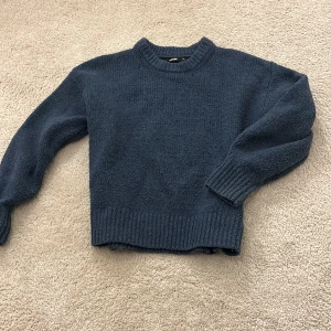 Blå stickad tröja från BikBok - Blå stickad tröja från BikBok i storlek XS. Tröjan har en rund halsringning och ribbade muddar vid ärmslut och nederkant.