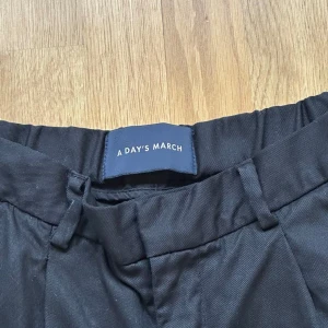 Svarta kostymbyxor från A Day's March - Säljer ett par svarta  kostymbyxor från A Day's March. Dem är lite ovetsize. 