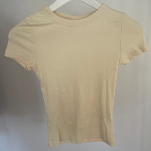 Beige ribbad t-shirt från H&M - Säljer en ljus gul ribbad t-shirt från H&M i storlek xs, endast testat 