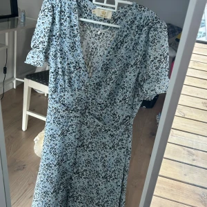 Ljusblå klänning - Supersöt ljusblå klänning med leopardmönster från Chelsea. Klänningen har v-ringning, puffiga korta ärmar och markerad midja. Perfekt för dig som vill sticka ut med ett trendigt mönster och luftig känsla. Påminner även om Adoore klänningar.