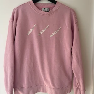 Rosa tröja från Adidas - Sparsamt använd och i bra skick, adidasmärkena på bröstet har börjat släppa en aning men lätt att åtgärda. Perfekt att ha till jeans eller kjol och lika snygg att ha i skolan som på helgen.