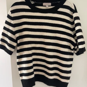 stickad t-shirt  - Säljer denna kortärmade stickade tröjan med svarta och vita ränder. Endast använd fåtal gånger. Strl L, se bild för hur den sitter på mig som vanligen har S