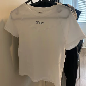 Vit t-shirt från Aim'n - Säljer en vit t-shirt från Aim'n med liten logga framtill. T-shirten har rund halsringning och är tillverkad i ett stretchigt material som passar perfekt till träning eller vardag. Enkel och stilren design.en compression shirts aldrig använd! 