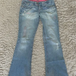Bootcut jeans - Skitsnygga jättelågmidjade bootcut/flared jeans med rosa detaljer. Köpta här på plick men var tyvärr för stora för mig därför säljer jag dom igen. Står ingen storlek men midjemåttet är 34 och innerben är 76. Skulle säga att de passar 34/36💞