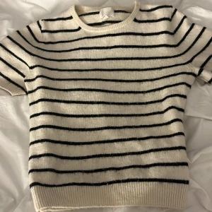 Randig tröja från H&M - Säljer en stilren randig tröja från H&M i svart och vit. Tröjan har korta ärmar och en rund halsringning, perfekt för en avslappnad look. priset kan diskuteras