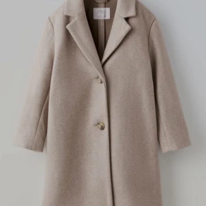 Beige kappa från Zara - Elegant beige kappa från Zarah barnavdelningen med klassisk design och knappar framtill. Perfekt för höst och vår, med en stilren look som passar till många tillfällen.