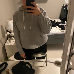 Grå hoodie - Säljer en klassisk grå hoodie med justerbar dragsko i huvan och en stor magficka. Perfekt för en avslappnad stil. Passar både för mysiga hemmakvällar och vardagsäventyr.