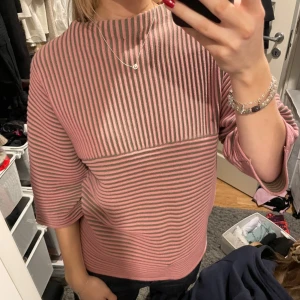 Rosa och grön randig tröja - Säljer en snygg rosa och grön randig tröja med trekvartsärm. Tröjan har en hög krage och en avslappnad passform. Perfekt för en stilren look! Skriv gärna för fler frågor!💕