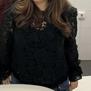 Svart spetsblus från Nelly - Säljer en elegant svart spetsblus från Nelly. Blusen har långa ärmar och vackra volangdetaljer. 🖤Ny pris: 499kr Mitt pris: 200kr❗️