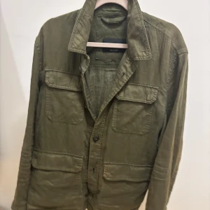 Grön overshirt från Massimo Dutti - Säljer en stilren grön overshirt från Massimo Dutti som är i linne material och är extremt snygg till sommaren då den är lätt och funkar som en perfekt overshirt nu till våren och sommaren. I storlek M med nypris 1500 från Massimo dutti.