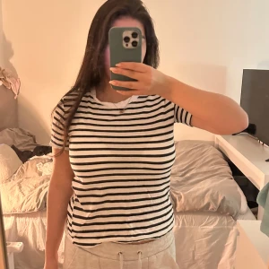 Randig t-shirt från Zara - Säljer en klassisk svartvit randig t-shirt från Zara. Den har en rund hals och korta ärmar, perfekt för en avslappnad stil. Passar bra till jeans eller shorts för en enkel look.