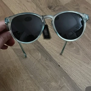 Transparenta solglasögon med svarta linser till barn från bliz  - Snygga solglasögon med transparent båge och svarta linser. Perfekta för en stilren look. Passar både till stranden och stadspromenaden. För barn 