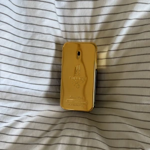 1 million parfym, paco robanne - Säljer en lyxig guldpläterad parfymflaska från Paco Rabanne. Flaskan har en elegant och modern design med en spegelblank yta och präglad logotyp. Perfekt för den som vill ha en exklusiv doftupplevelse.