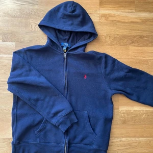Mörkblå hoodie från ralph lauren - Säljer en snygg mörkblå hoodie från Ralph Lauren med dragkedja och huva. Den passar storlek 160. Den är i mycket bra skick