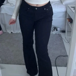 Svarta petite bootcut jeans - Snygga svarta bootcut jeans med låg midja och klassisk femficksdesign. Perfekta för en stilren look. Passar bra till både vardag och fest.