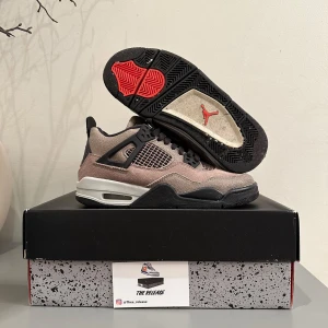 Nike Air Jordan  - Snygga Nike Air Jordans i en kombination av mocka och syntet. Skorna har en stilren design med grå och svarta toner samt röda detaljer. De har snörning och en ikonisk logga på hälen. Perfekta för dig som vill ha en klassisk sneaker med en modern twist.