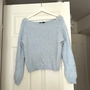 Ljusblå fluffig tröja från Gina Tricot - Mysig ljusblå tröja från Gina Tricot med en fluffig textur. Tröjan har en bred halsringning och långa ärmar, perfekt för kyligare dagar. Den är både stilren och bekväm, vilket gör den till ett utmärkt tillskott i garderoben. Supermjuk