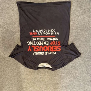 Svart t-shirt med tryck - Säljer en svart t-shirt med ett humoristiskt tryck i vitt och rött. Perfekt för dig som vill ha en avslappnad stil med en rolig twist. T-shirten har korta ärmar och en rund halsringning.