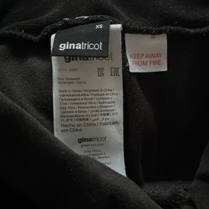 Svarta byxor från Gina Tricot - Snygga svarta byxor från Gina Tricot i en mjuk och bekväm design. Byxorna har en hög midja och vida ben, vilket ger en trendig look. Perfekta för en stilren outfit.
