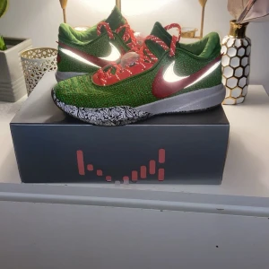 Gröna och röda Nike sneakers - Snygga gröna och röda Nike sneakers med ett unikt mönster på sulan. Skorna har en iögonfallande design med röda snören och en vit Nike-logga på sidan. Jätte snygga basket skor lebron James 20 Christmas modell jag har allt med den dom är som nya använda några gånger med jätte bra skick kvitto och allt man köper får man med original skosnörena finns också med i lådan pris kan diskuteras vid snabb affär :)
